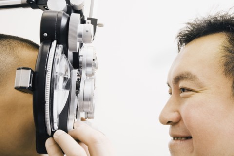 Asian male optometrist examining patient