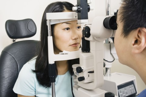 Asian male optometrist examining patient