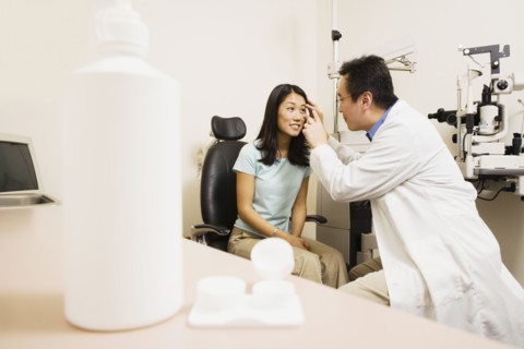 Asian male optometrist examining patient