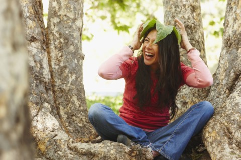 Hispanic woman sitting outdoors with leaf on her head