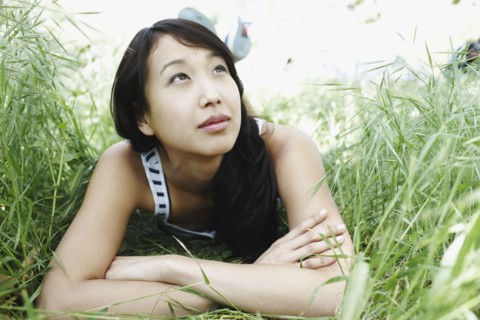 Asian woman laying in grass
