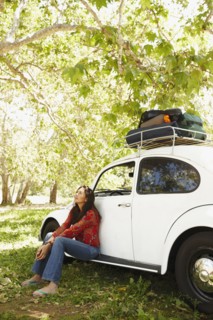 Hispanic woman sitting on side of car