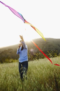 Asian woman flying kite in field