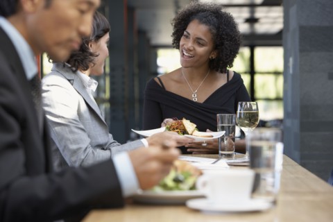 African waitress bringing food to businesswoman