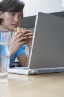 Hispanic woman looking at laptop and eating