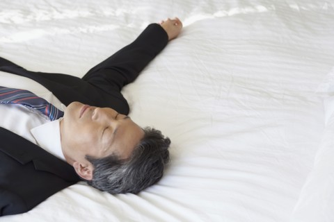 Asian businessman laying on bed
