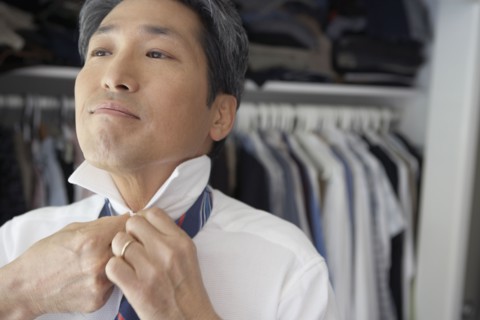 Asian businessman putting on tie
