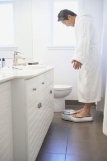 Asian man standing on bathroom scale