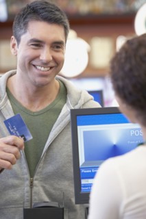 Hispanic man holding up credit card at check out