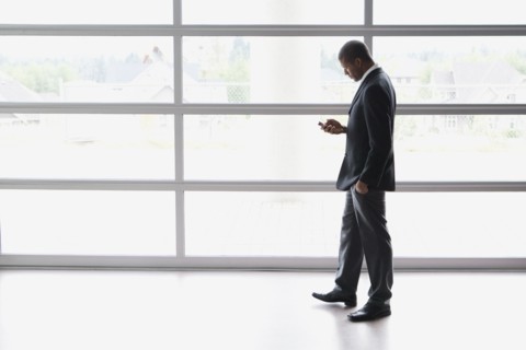 African businessman text messaging on cell phone