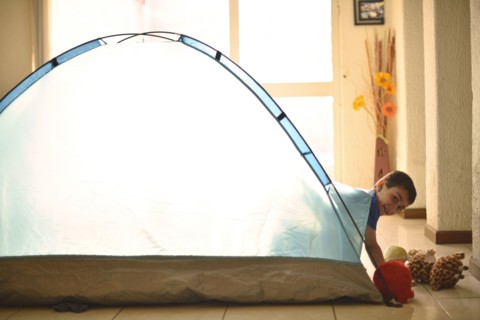 Hispanic boy camping in tent indoors