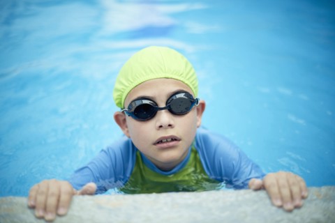 Hispanic boy swimming with swimming cap and goggles