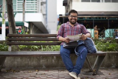 Hispanic man sitting on bench reading brochure