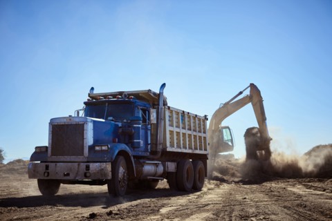 Truck near digger in dirt field