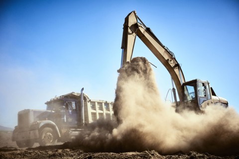 Truck near digger in dirt field