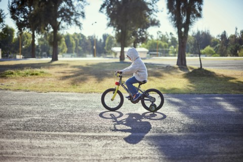 Hispanic boy riding bicycle with training wheels