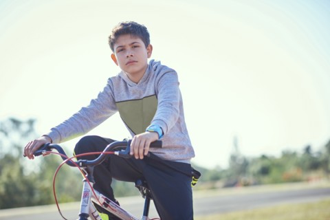 Serious Hispanic boy posing on bicycle