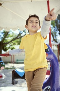 Hispanic boy on carousel at playground