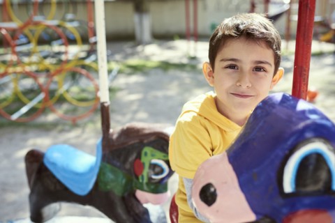 Hispanic boy on carousel at playground