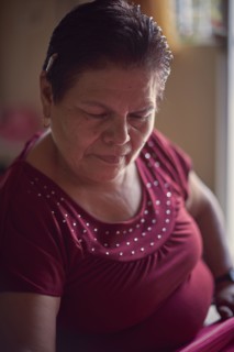Hispanic woman weaving fabric on loom