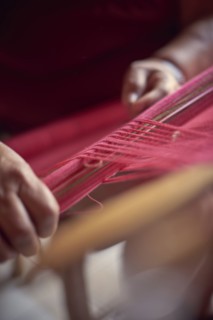 Hispanic woman weaving fabric on loom