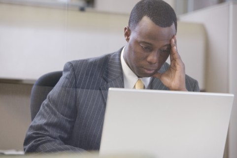 Stressed African businessman working on laptop