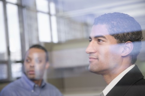 Two businessman behind window glass