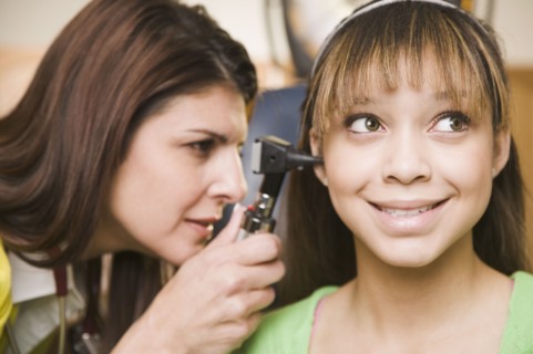 Mixed race doctor examining teenage girl's ears