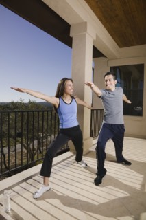 Hispanic couple doing yoga on balcony