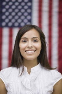 Hispanic woman standing near American flag