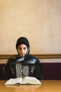 Middle Eastern teenager in headscarf reading book