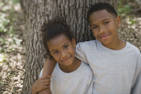 African boy and girl hugging against tree
