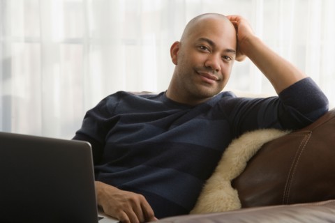 Mixed race man sitting in chair with laptop