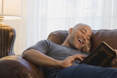 Mixed race man in armchair reading book