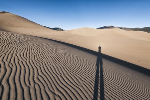 Shadow of person on sand dunes