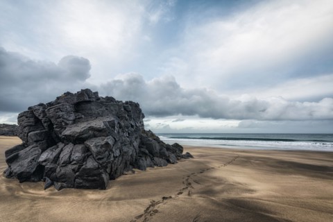 Footprints on beach near rock formation