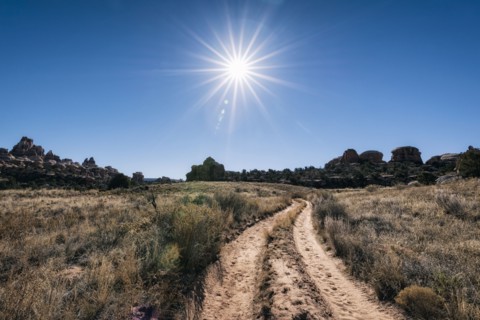 Sun in blue sky over desert path