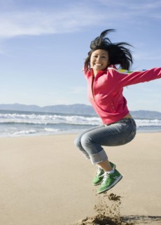 Asian woman jumping on beach