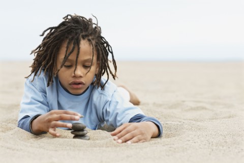 Mixed Race boy stacking stones on sand
