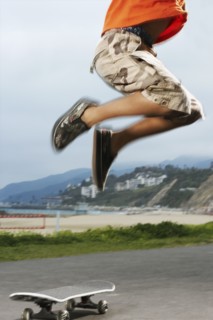 Mixed Race boy jumping over skateboard
