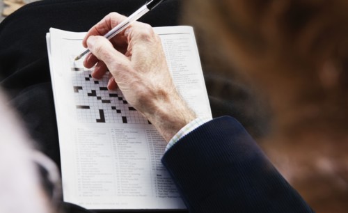 Close up of senior man's hand with pen on crossword puzzle