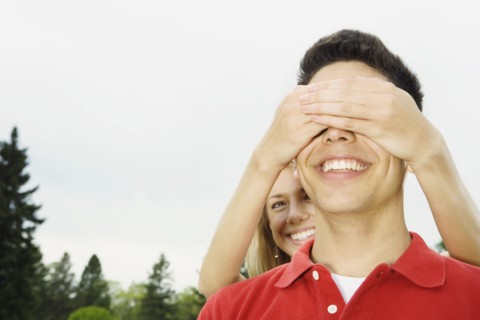 Woman covering boyfriend's eyes