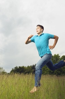 Young man running barefoot in meadow
