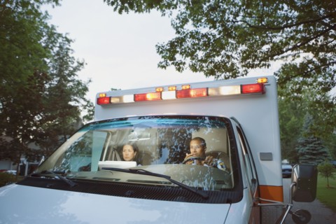 Male and female paramedics in cab of ambulance