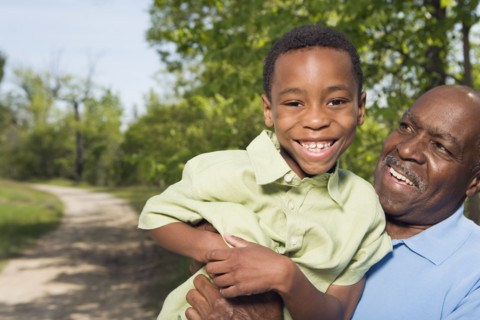 African grandfather holding grandson in park
