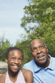 African grandfather and granddaughter looking up in park
