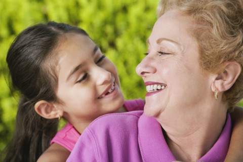 Hispanic grandmother and granddaughter smiling at each other