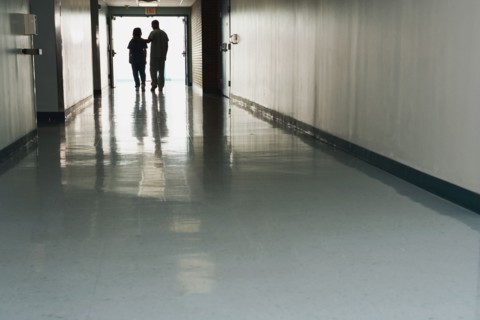 Two people standing at end of corridor in hospital