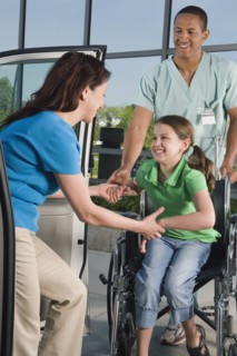 Hispanic girl in wheelchair leaving hospital with mother