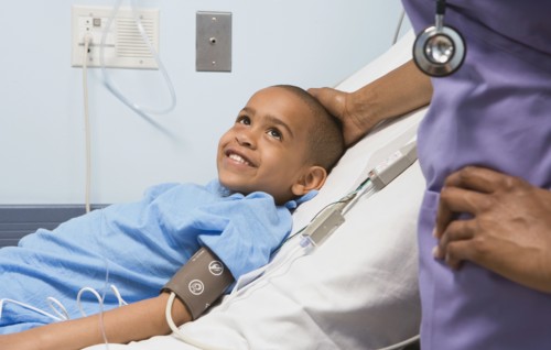 African boy smiling at nurse in hospital bed